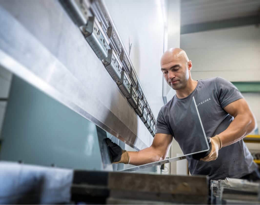 Ein Mitarbeiter von Zaitschek biegt ein Blechteil in einer Biegemaschine